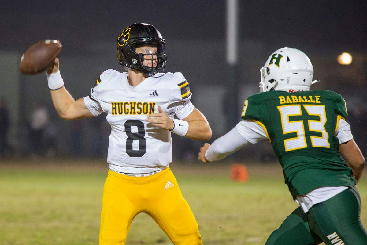 Hughson’s Robert McDaniel, 8, looks up field for a receiver under pressure from Hilmar’s Nicholas Baballe, 53, during the Trans-Valley League game with Hilmar in Hilmar Friday Oct. 25, 2024.