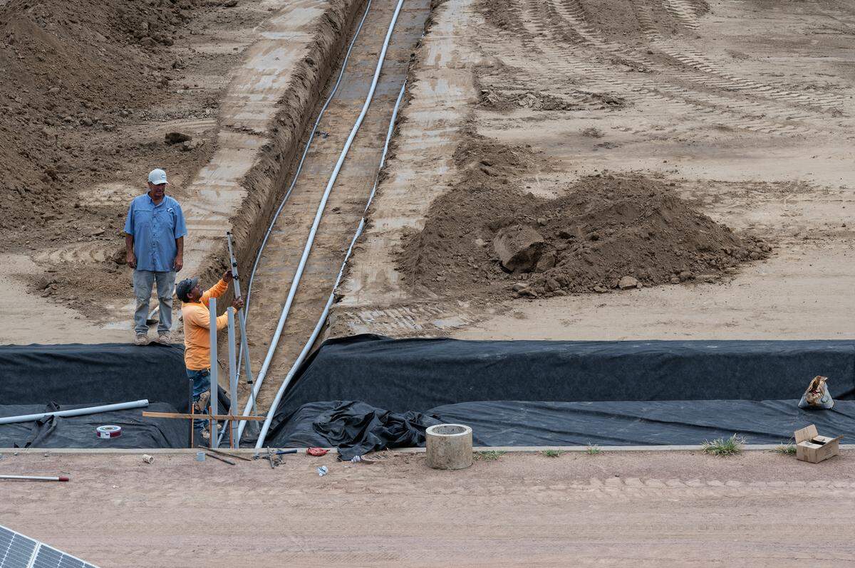 A crew works on the foundation for a new artificial turf at Johansen High School in Modesto, Calif., on Friday, August 5, 2022.