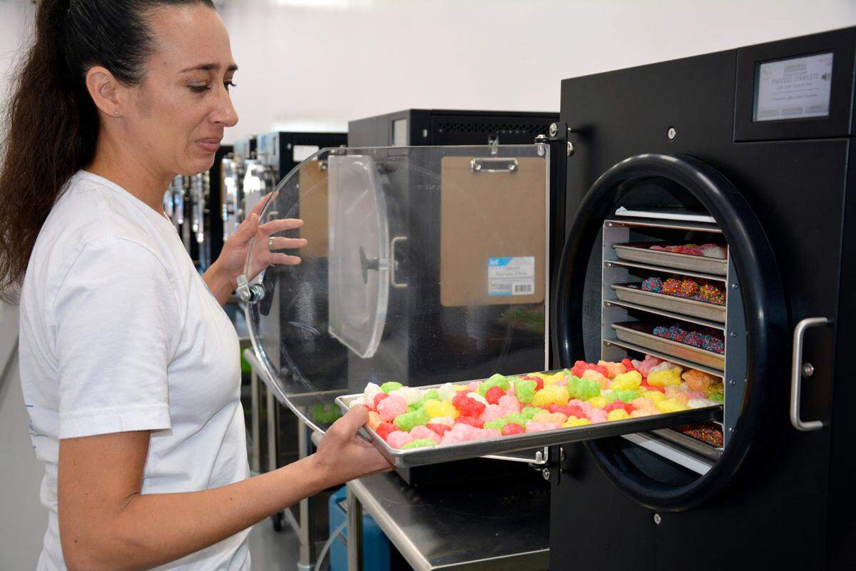The Parched Goat owner Megan McMenimen takes freshly freeze-dried candies out of the machines in her Hughson sweets and snacks shop July 12, 2023.