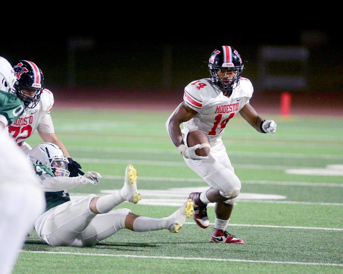 Modesto High running back Vanntheesouk ‘Lucky’ Dam (14) breaks away from Central Valley defenders during a game between Modesto High School and Central Valley High School at Gregori High School in Modesto, Calif., on Sept. 13, 2024.