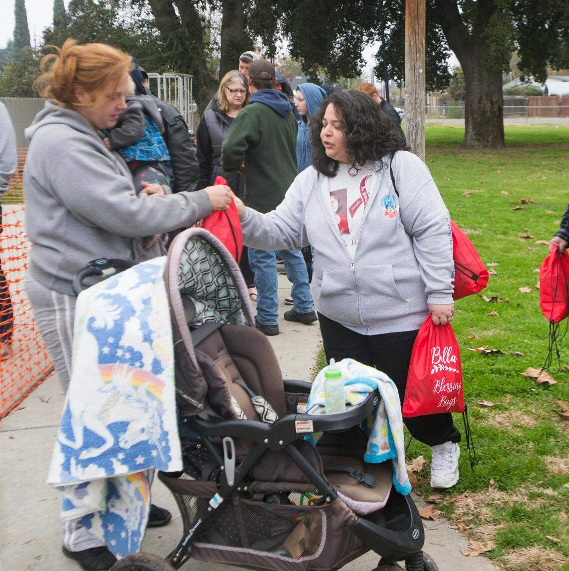 Melissa Regacho, right, along with her husband Josh Regacho spent Sunday Dec. 9, 2018 morning at Oregon Park handing out Bella Bags in honor of their daughter that passed away from meningitis in 1999.