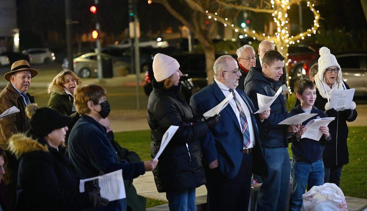 A small group sings with Congregation Beth Shalom Rabbi Shalom Bochner during the lighting of the menorah on the third day of Hanukkah outside the Gallo Center for the Arts in Modesto, Calif., Tuesday, Dec. 20, 2022.