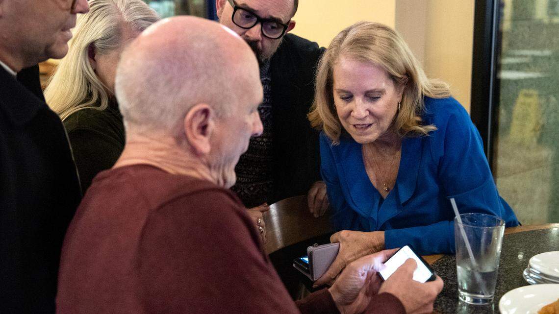 Modesto Schools superintendent Sara Noguchi, right, and board member Chad Brown, left, look at early results for Measure L with other supporters at Fuzio restaurant in Modesto Calif., Tuesday, Nov. 8, 2022.