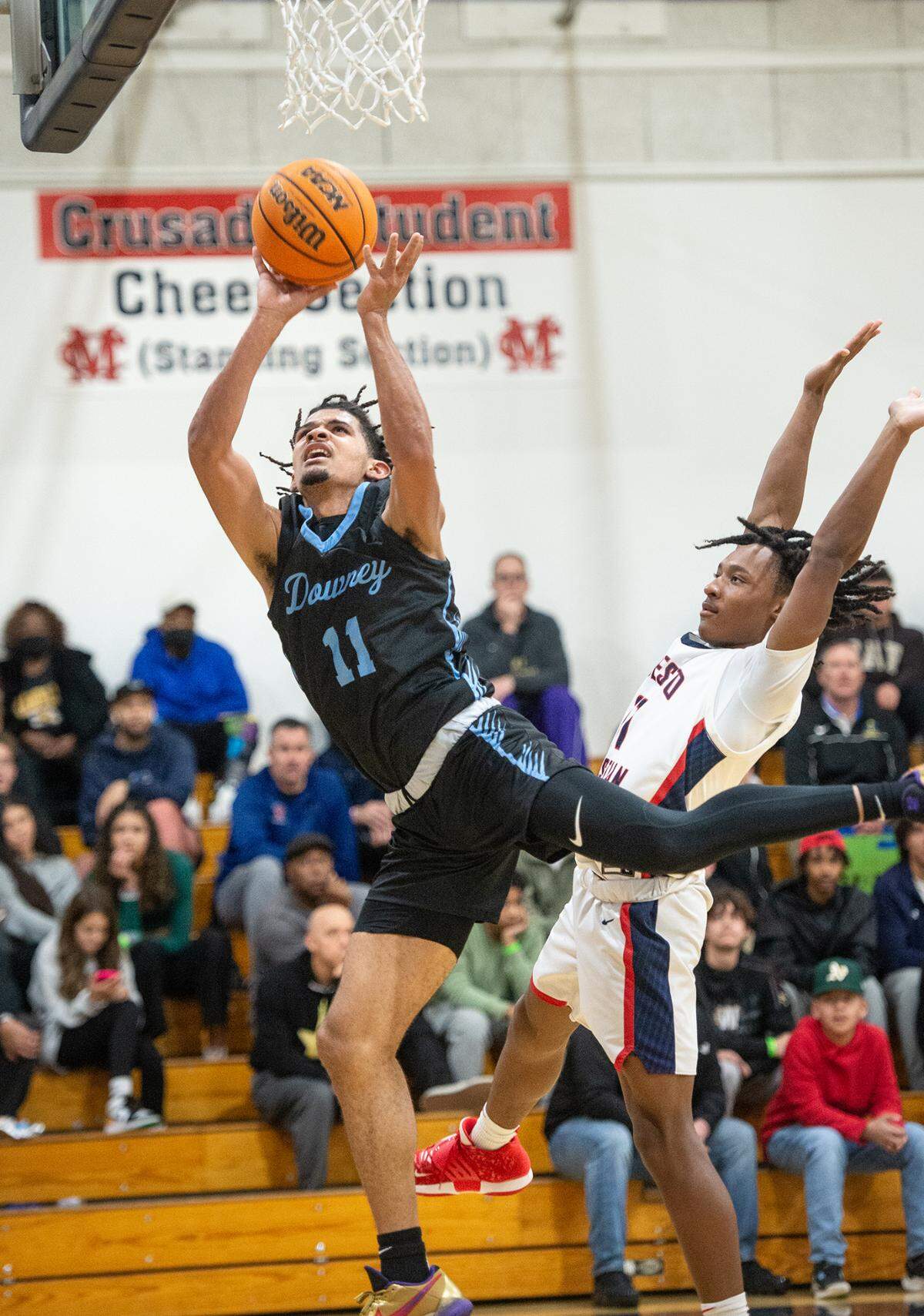 Downey’s Lloyd French (11) scores a layup past Modesto Christian’s BJ Davis during the Modesto Christian Holiday Hoop Classic in Salida, Calif., Tuesday, Dec. 27, 2022.