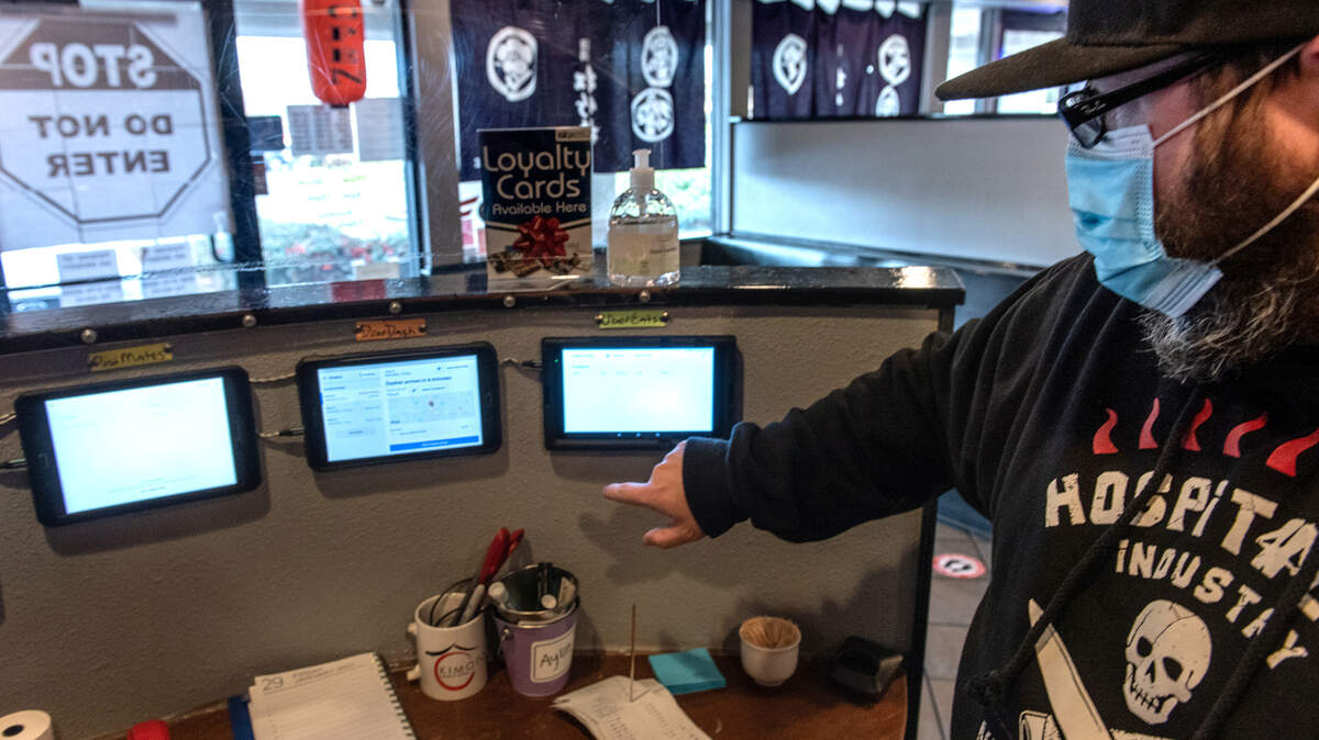 Owner Brandon Dodge points to the tablets for delivery services like DoorDash at Kimoto Sake & Sushi in Modesto, Calif., on Saturday, Jan. 30, 2021.