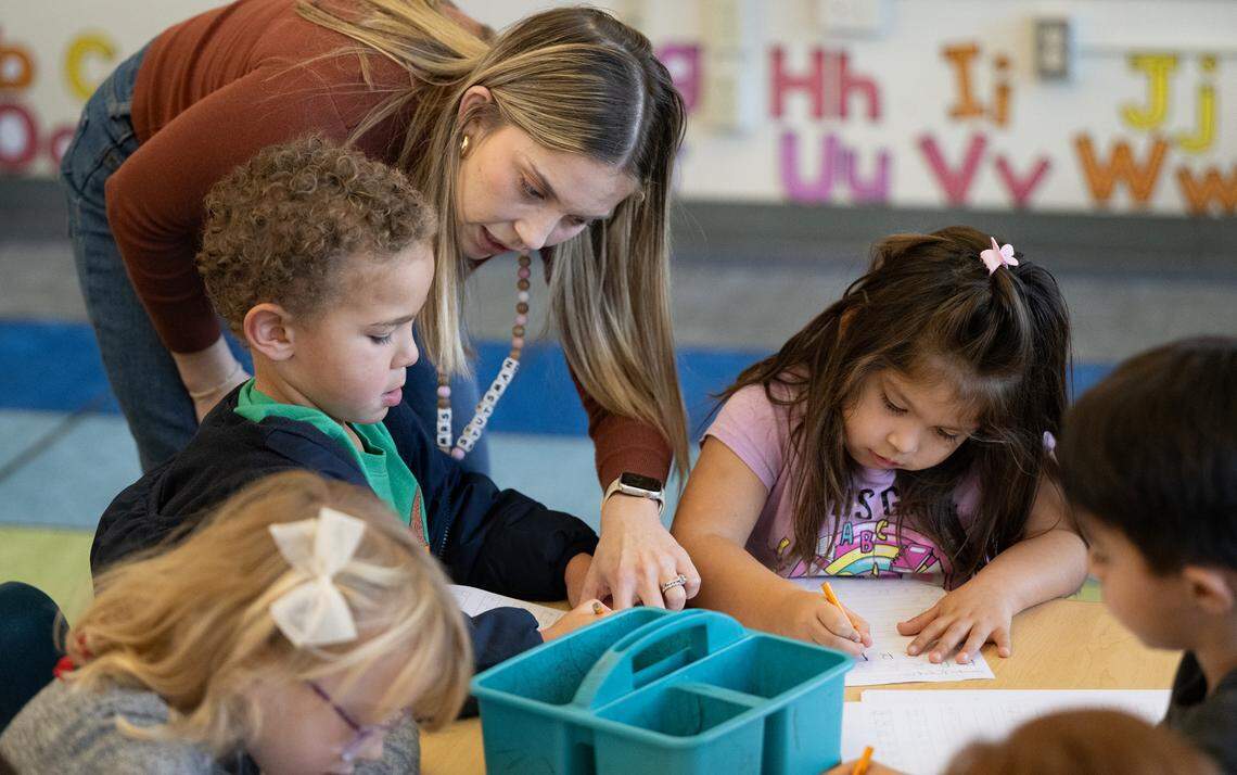 Transitional kindergarten teacher Morgan Stutsman helps student Leo Nelson, left, during a handwriting exercise at Fremont School in Modesto , Calif., Thursday, Dec. 7, 2023. The kindergarten students are working on motors skills and letter recognition to prepare them for cursive writing in later grades. In October, Gov. Gavin Newsom signed a law requiring cursive handwriting instruction mandatory in first through sixth grades effective Jan. 1.