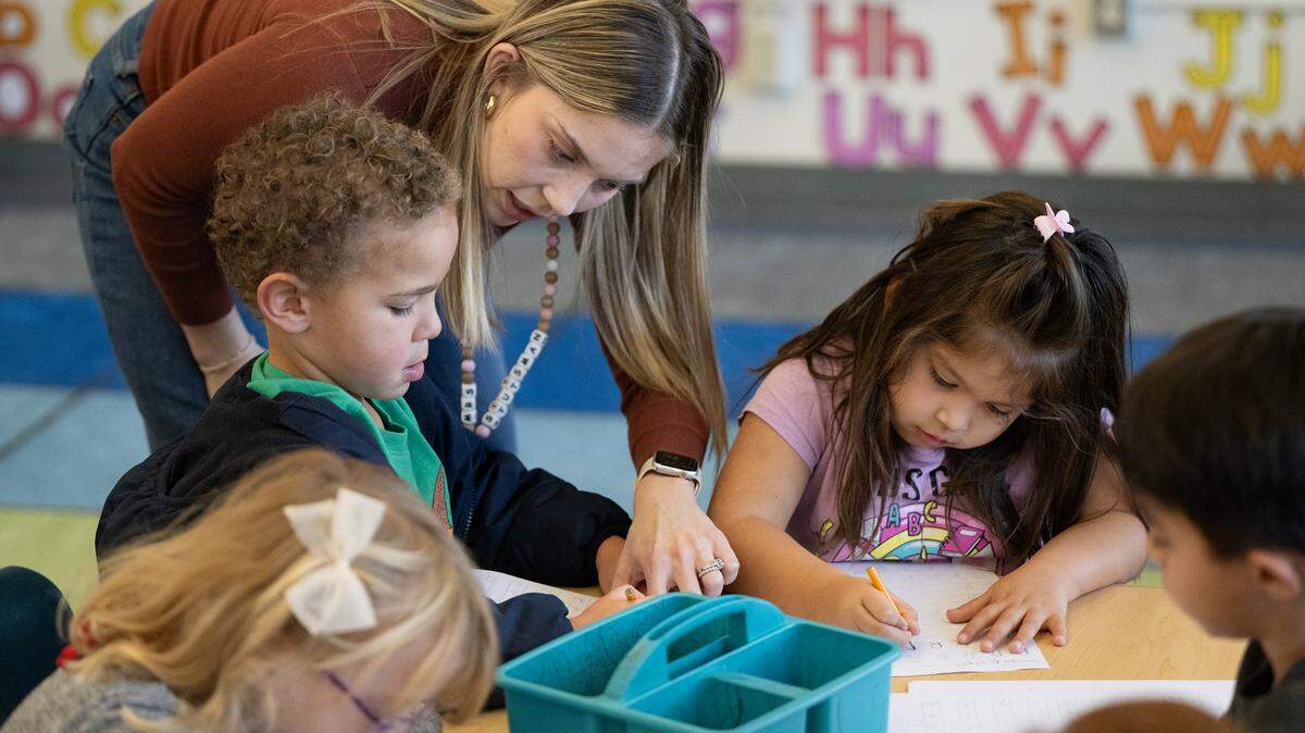 Transitional kindergarten teacher Morgan Stutsman helps student Leo Nelson, left, during a handwriting exercise at Fremont School in Modesto , Calif., Thursday, Dec. 7, 2023.