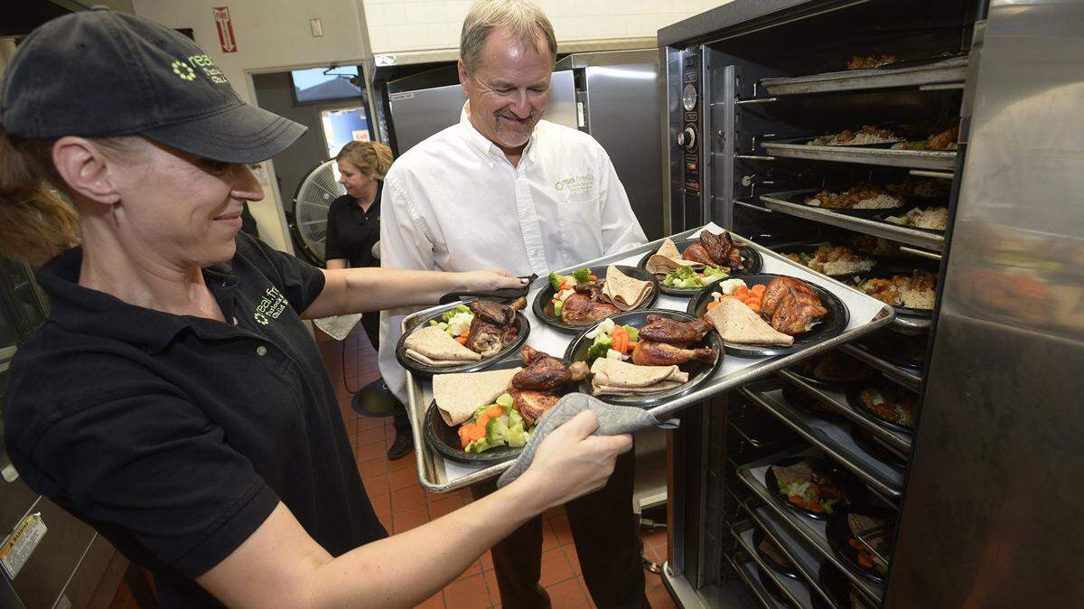 Sandy Sessions (left) with a tray of rotisserie chicken just plated and ready to go as Scott Soiseth, Child Nutrition Director looks on in preparation for lunch at Turlock High School.