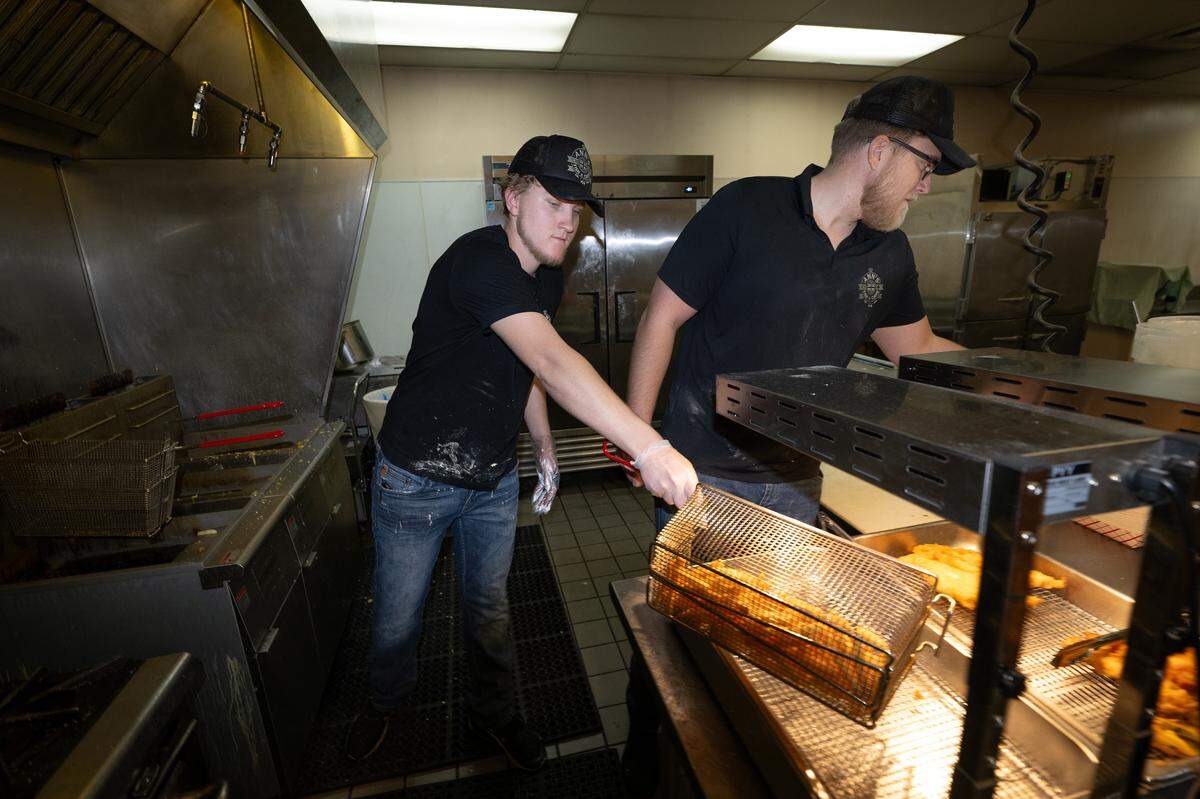 Cook Wyatt Moring, left, and owner Ryan Donnelly work in the kitchen at Ann’s Fish & Chips in Hughson, Thursday, April 17, 2025.