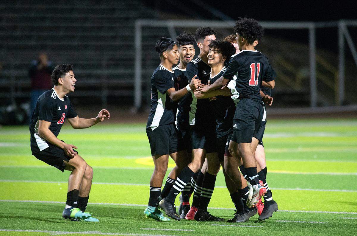 Modesto’s Alexis Luna is swarmed by his teammates after scoring a goal in the first half the Sac-Joaquin section playoff game with Folsom at Downey high School in Modesto, Calif., on Thursday, Feb. 10, 2022. Luna scored all three goals in Modesto’s 3-0 victory.