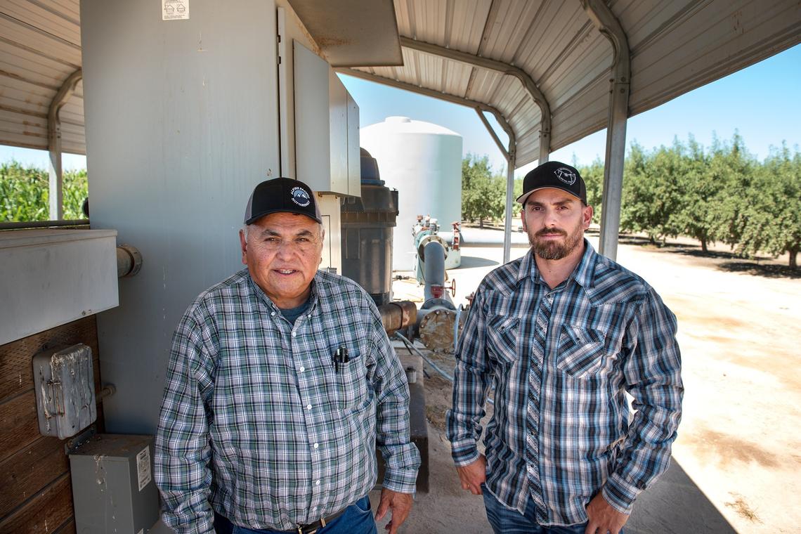 Darrell Cordova, left, and son Trevor stand at one of their pump sites at their farm in Denair Calif., Tuesday, July 24, 2018. The farm uses only groundwater for irrigation.