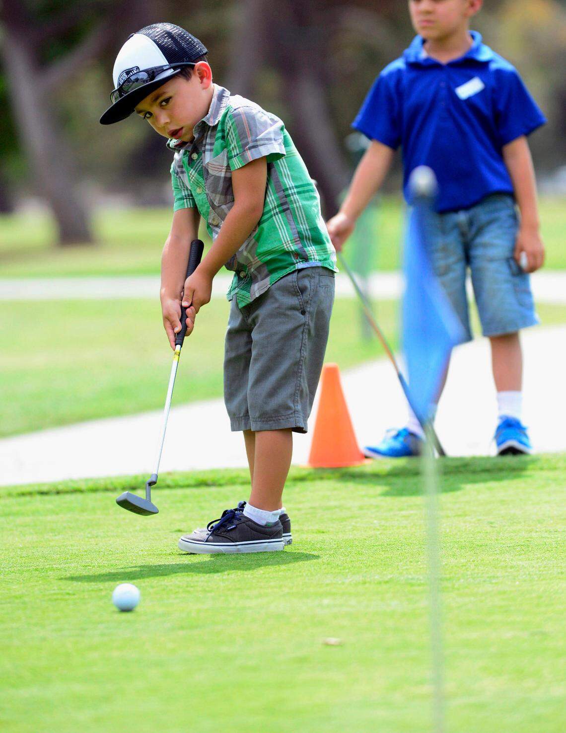 Davis Cornell leans as he observes his putt while it heads toward the hole during the First Tee Central Valley youth golf program at the Modesto Municipal Golf Course in 2014.