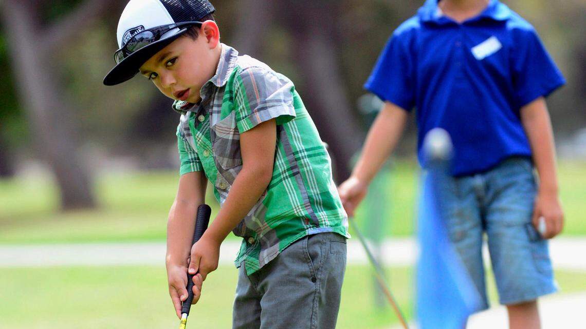 Davis Cornell leans as he observes his putt while it heads toward the hole during the First Tee Central Valley youth golf program at the Modesto Municipal Golf Course in 2014.
