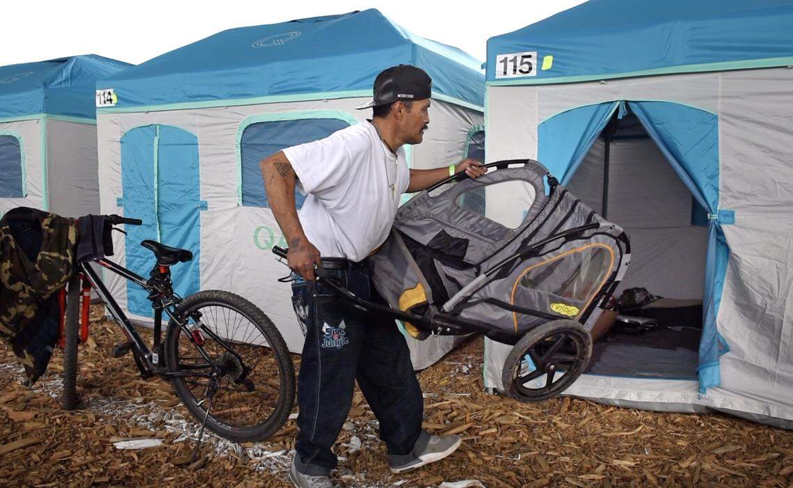 Junior Lopez moves into his tent at the new Modesto Outdoor Emergency Shelter for the homeless under the Ninth Street Bridge in Modesto, Calif., Wednesday, Feb. 20, 2019.