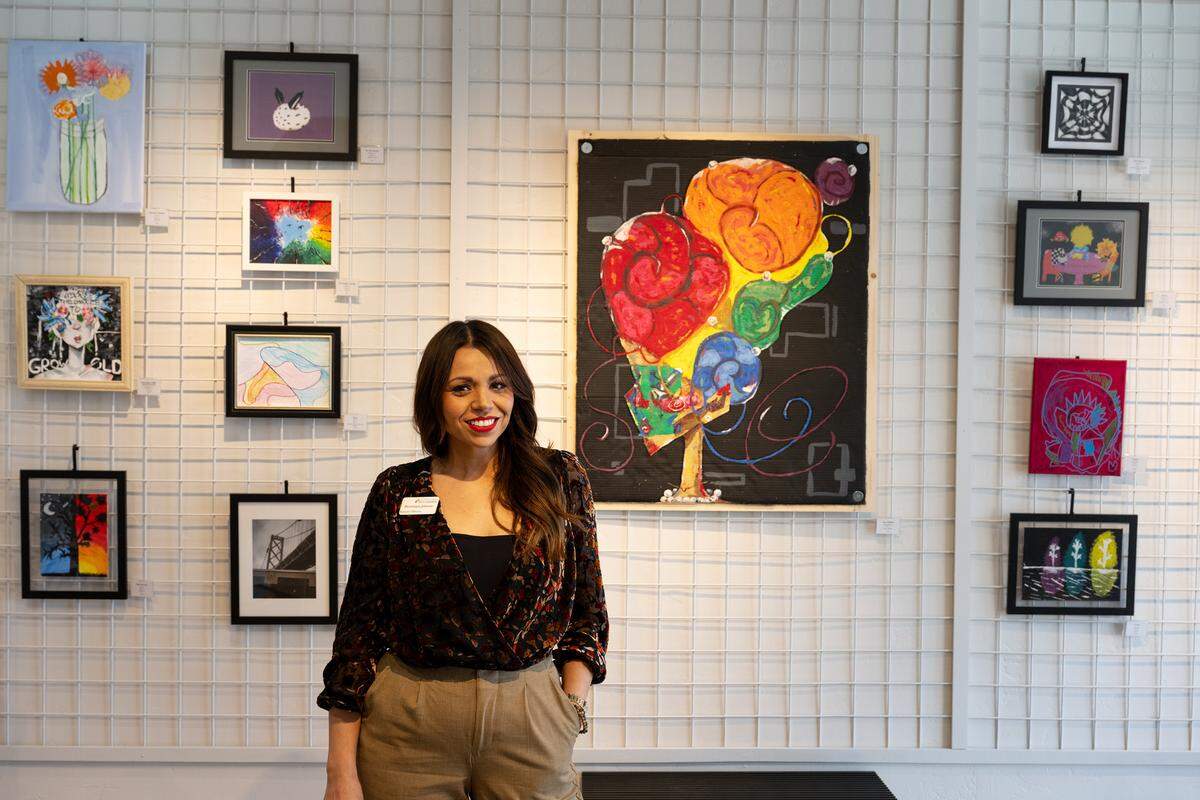 Stanislaus Arts Council Executive Director Dominique Johnson stands with the gallery’s current exhibition of work from young artists in Modesto Thursday, March, 6, 2025.