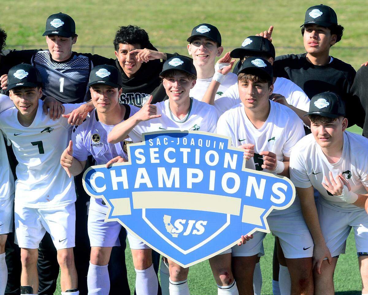 Pitman soccer players hold the section championship sign after winning the Sac-Joaquin Section Division II championship against Woodcreek High School at Cosumnes River College in Sacramento, Calif. on Saturday, March 1, 2025.