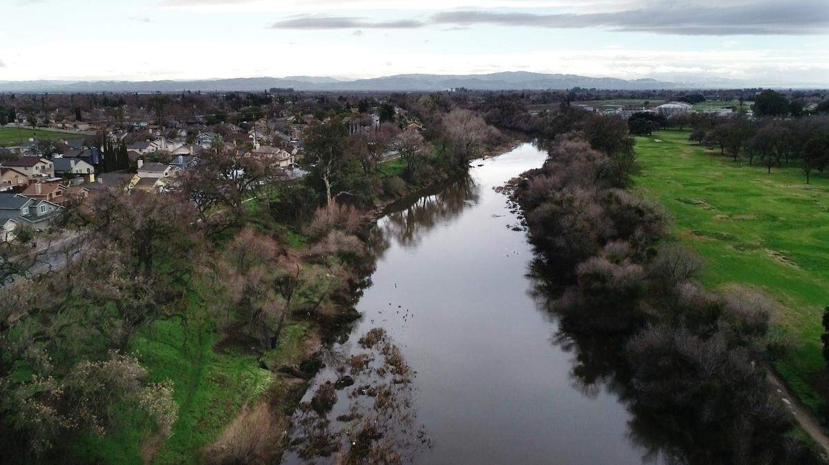 Looking west, the Tuolumne River flows between the Dryden Park Golf Course on the right and Crater Avenue neighborhood, left, in south Modesto, Calif., Thursday, Jan. 5, 2023. The river is expected to reach the 55-foot flood stage by Tuesday evening, as more rainstorms are in the forecast for this weekend and early next week, according to an update Friday from the Stanislaus County Office of Emergency Services.
