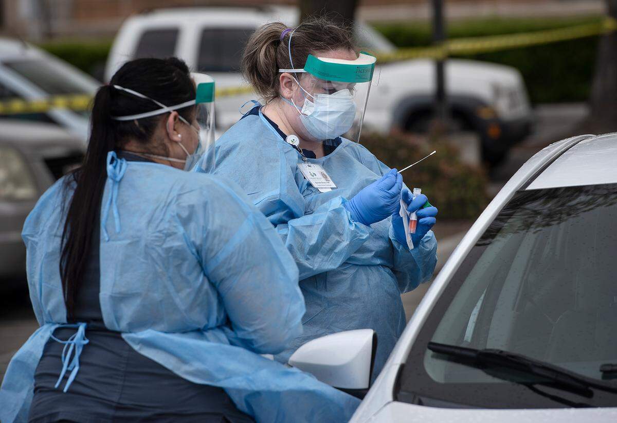 Nurse practitioner Danielle Groce administers a COVID-19 test at a Golden Valley Health Center test station in Ceres, Calif., on Wednesday, March 25, 2020. Medical assistant Maria Aragon, left, helps with translation. GVHC have two drive-thru viral testing sites, one in Ceres and one in Merced, but these are available only for GVHC clients from 9 a.m. to 3 p.m. with a referral from their provider.