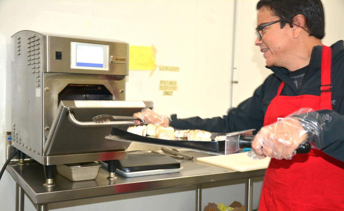 Fabricio Bernal, owner of Porky Wow, puts chicharrones in an oven to flash-bake in Turlock, Calif. Nov. 16, 2022.
