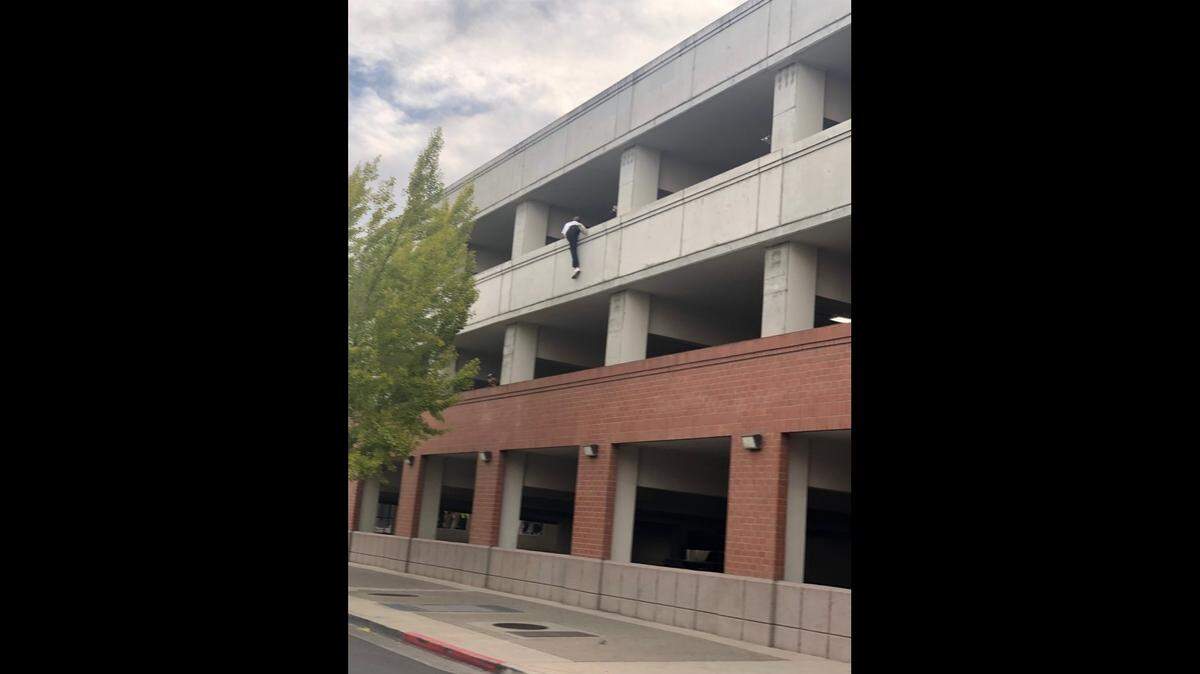 A car theft suspect clings to the third-story wall of a downtown Modesto parking garage along K Street on Sunday morning, Oct. 17, 2021.