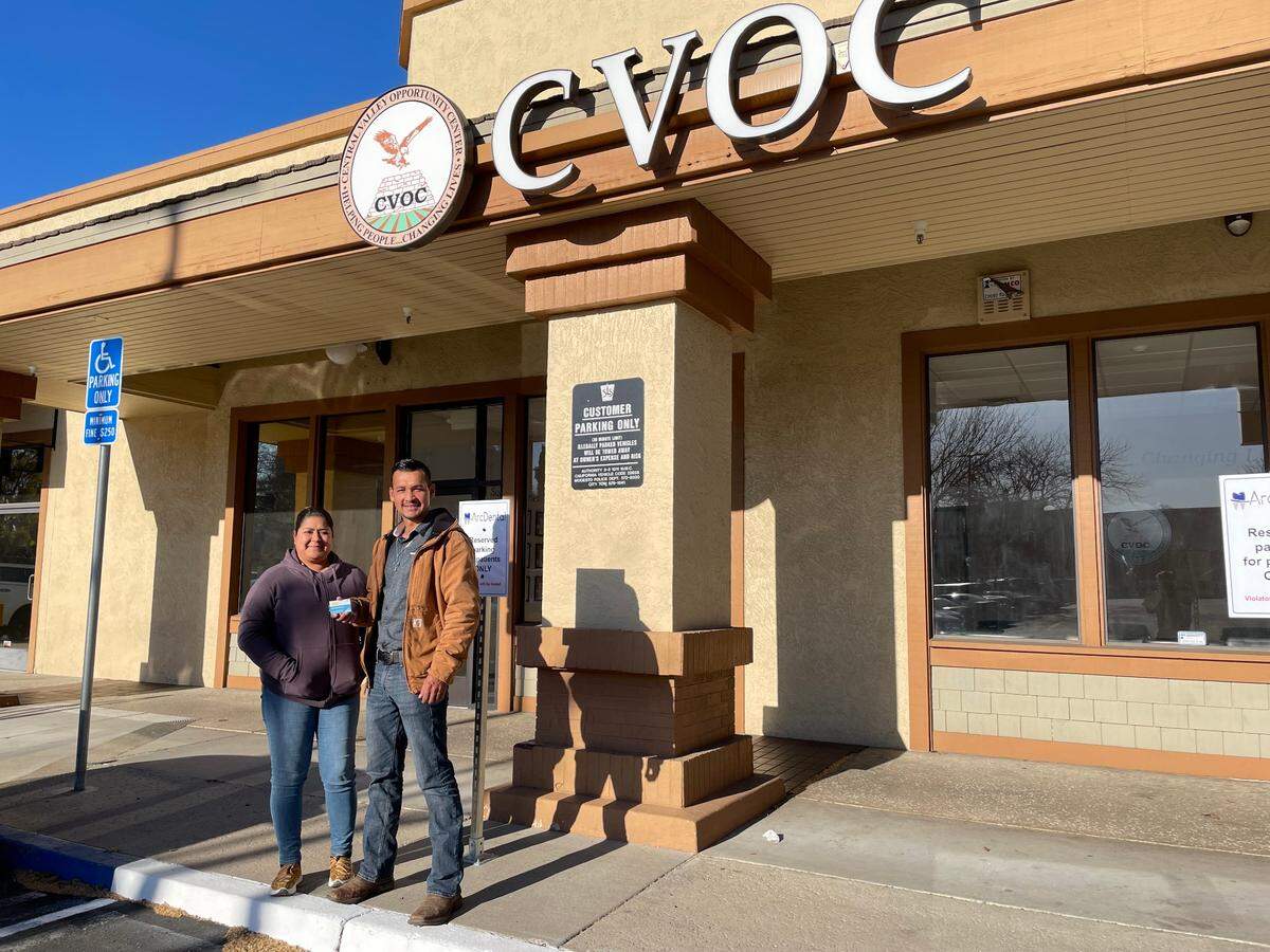 Victor Reynaga and Patricia Mendoza stand outside of the Central Valley Opportunity Center, which distributed $600 COVID-relief payments to each of them for their time as farmworkers.