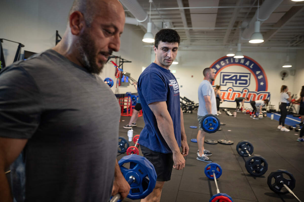 F45 coach Matt Sorisho, middle, helps Kaiser Yousif with lifting technique at F45 Training in Modesto on Tuesday, June 3, 2025.