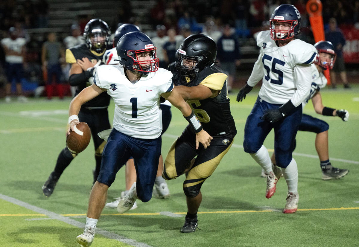 Beyer quarterback Nolan Foehringer scrambles away from an Enochs defender during the Sylvan Bowl at Downey High School in Modesto, Calif., Friday, Aug. 23, 2024.