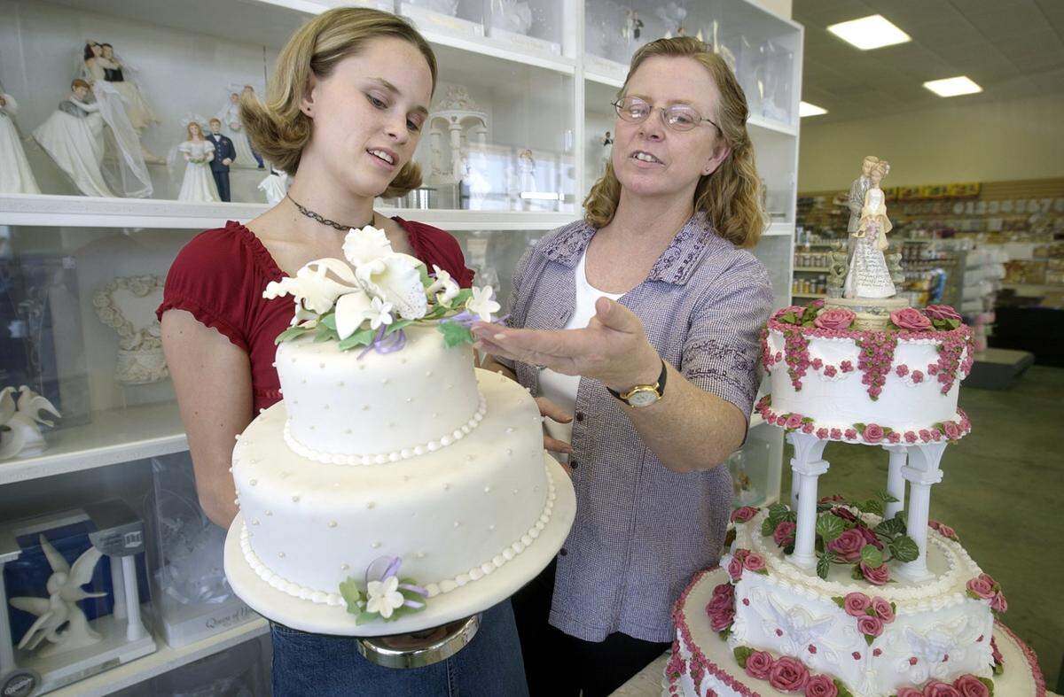 BART AH YOU / THE MODESTO BEE-- Edwards Cake and Candy Supplies, April Hawn and mother, former owner Carol Hawn examining "Rolled Fondant" style wedding cake next to more traditional cake set on a table, Monday, June 18, 2003.