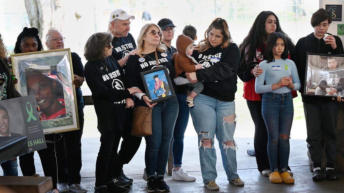 Darlene Ruiz holds a picture of her son, Trevor Seever, as she and members of the Seever family, middle, participate in a gathering of families impacted by police shootings in March. The solidarity lunch included impact statements and music at Graceada Park in Modesto, Calif., Saturday, March 25, 2023.