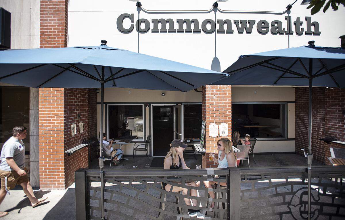 Sisters Rachael Schilber, and Rebecca Ellis, middle, enjoy a drink outside at Commonwealth in Modesto, Calif., on Thursday, May 21, 2020.