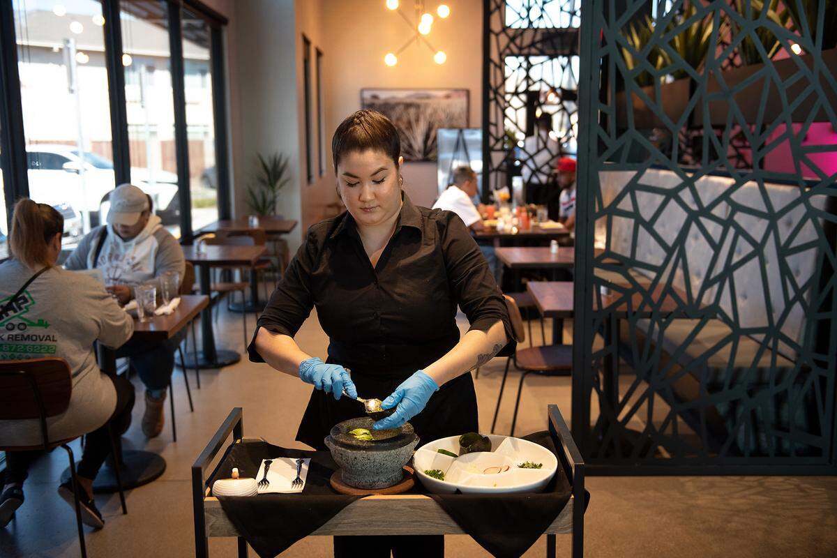 Savannah Havens prepares guacamole table side at Memo’s Cocina & Tequila Bar in Modesto, Calif., on Thursday, Feb. 24, 2022.