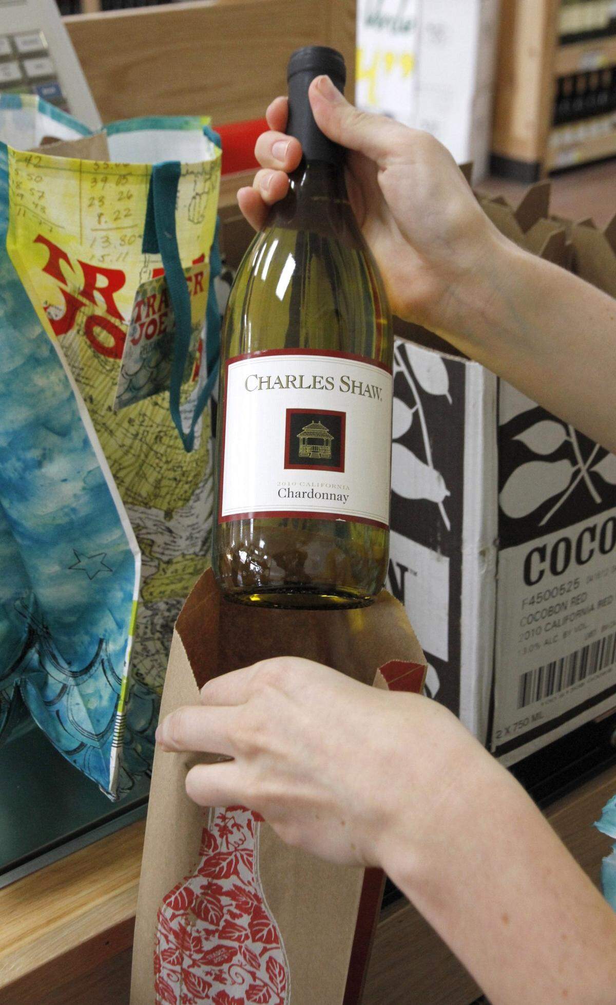 In this 2012 photo taken at a Trader Joe’s in Lexington, Ky., a bottle of Charles Shaw wine, aka Two Buck Chuck, is bagged for a customer.