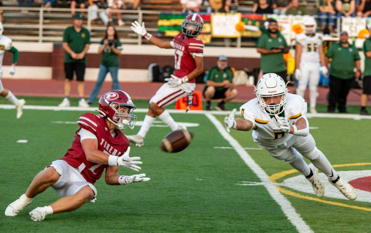 Daylen Paul, 0, of Hilmar High misses an attempt for an interception as Noah Cozart, 2, of Patterson makes the catch.