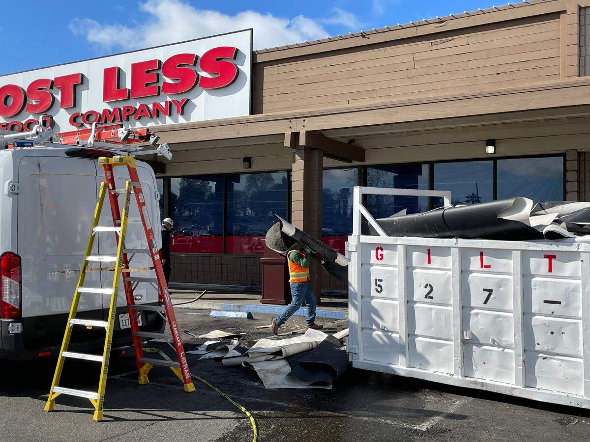 A worker hauls away part of the roof of Cost Less Food Company in Oakdale after a part of the roof collapsed during heavy rain on Monday, March 17.