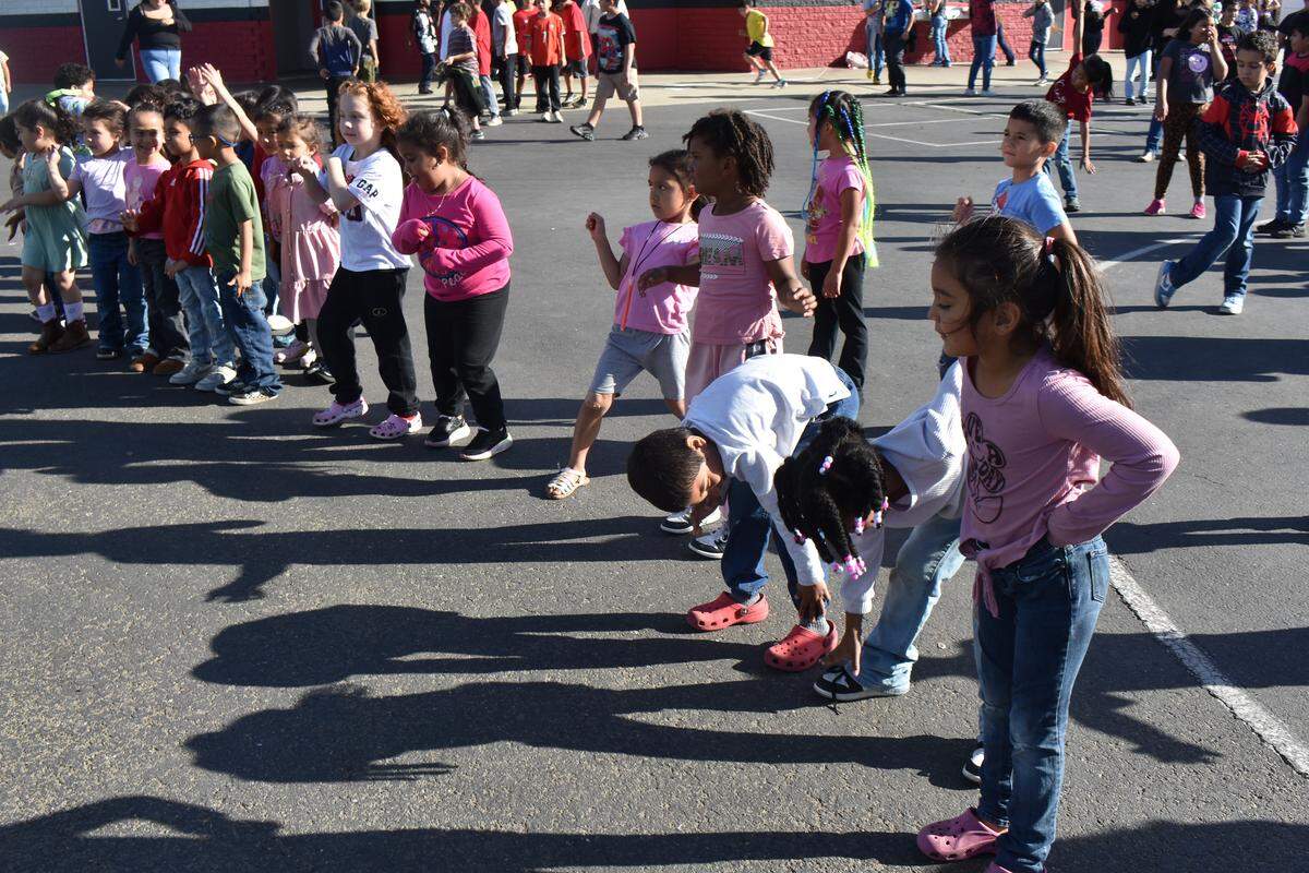 Whether by stretching or dancing, students at Modesto’s Robertson Road Elementary School warm up for their regular Friday afternoon 1-mile run around a school field. Photographed Nov. 7, 2025.
