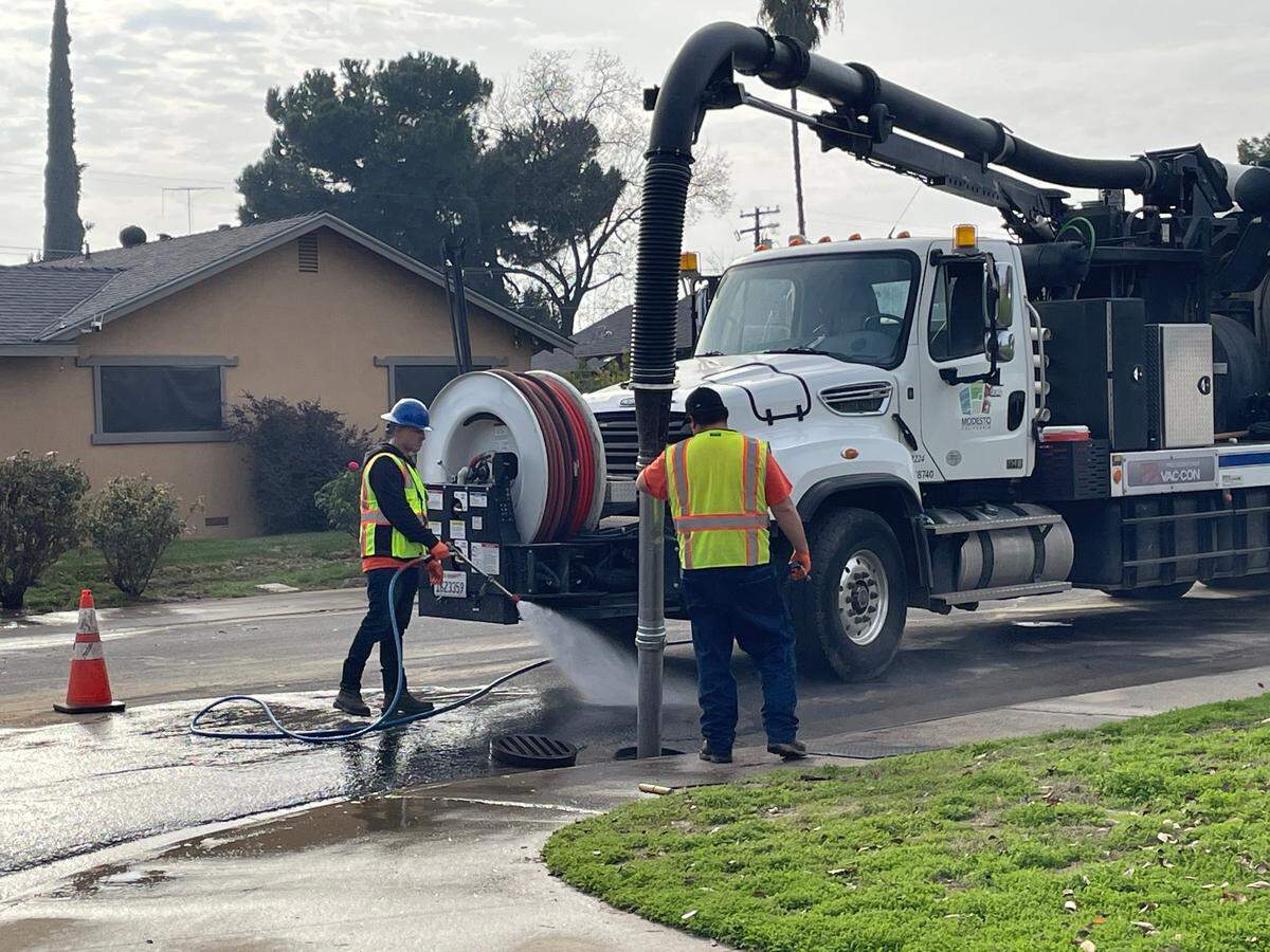 A crew clears out a clogged storm drain in northwest Modesto, Calif., on Dec. 23, 2024. It is on Budd Street, which was flooded after a water line break the previous day.