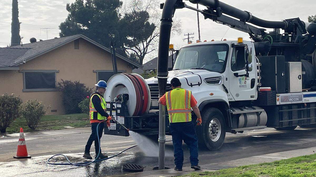 A crew clears out a clogged storm drain in northwest Modesto, Calif., on Dec. 23, 2024. It is on Budd Street, which was flooded after a water line break the previous day.