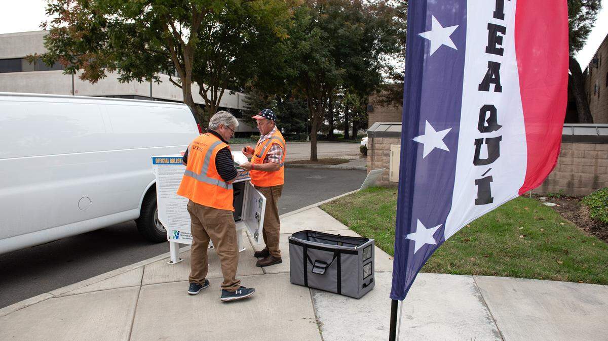 Election clerks Jack Tietjen, left, and Tom Soto collect ballots from a drop box outside the Salida library vote center in Salida, Calif., Saturday, Nov. 5, 2022.