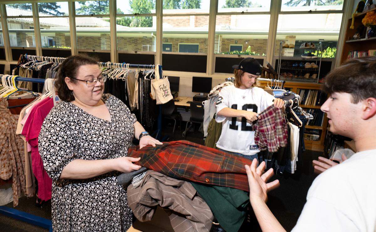 Turlock Thrift Club adviser Virginia Barr helps sort donations with club members David Romero, right, and Xavier Bettencourt, middle, in the school store at Turlock High on Wednesday, Aug. 20, 2025.