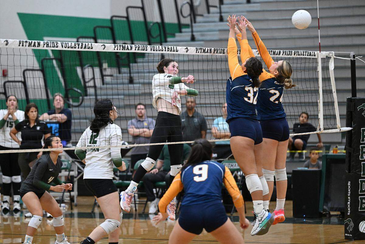 Pitman’s Maryn Hall spikes the ball past Oak Ridge defenders Lizi Horning (32) and Riley Elliott (24) during the non-league match at Pitman High School in Turlock, Calif., Thursday, September 7, 2023. Oak Ridge won the match 3-2.