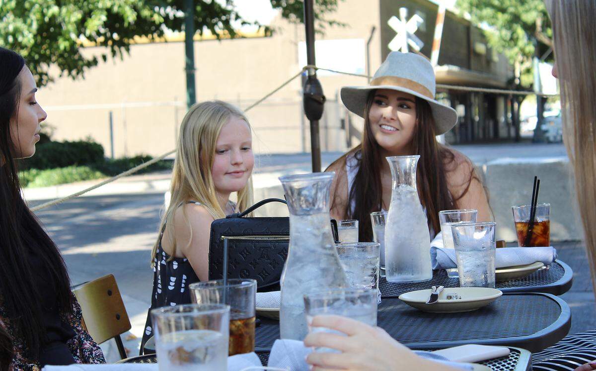 Cousins Cassie Kroll (right) and Sophie Mahoney (left) listen to a family conversation while dining in the street in Turlock, Calif. on July 23, 2020.