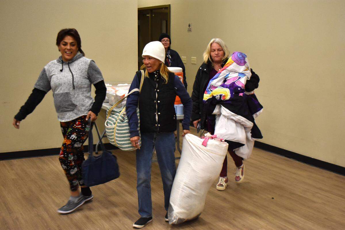 Elizabeth Godinez, left, and others arrive at the Modesto Gospel Mission on Yosemite Boulevard on Thursday night, Nov. 9, 2023.