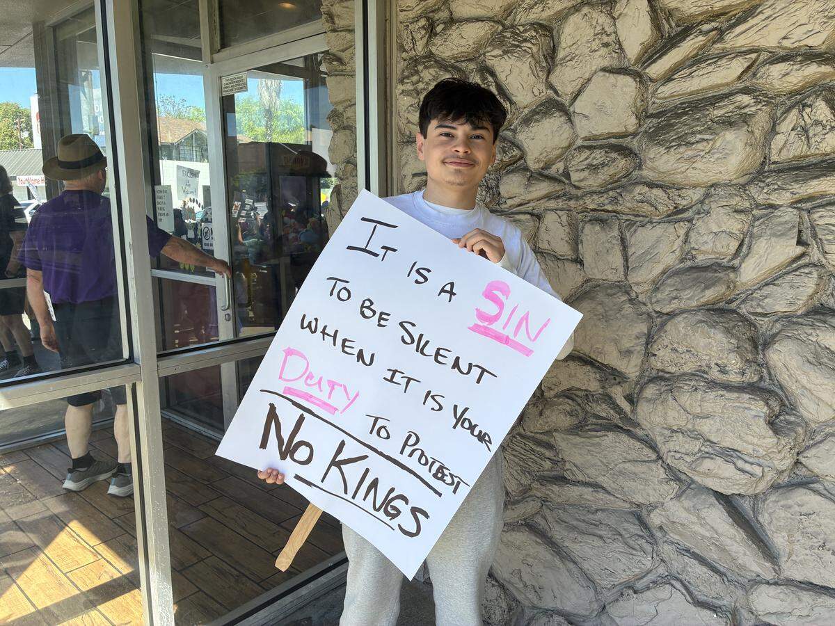 A 17 year old student holds a sign that reads “It is a sin to be silent when our duty is to protest.”