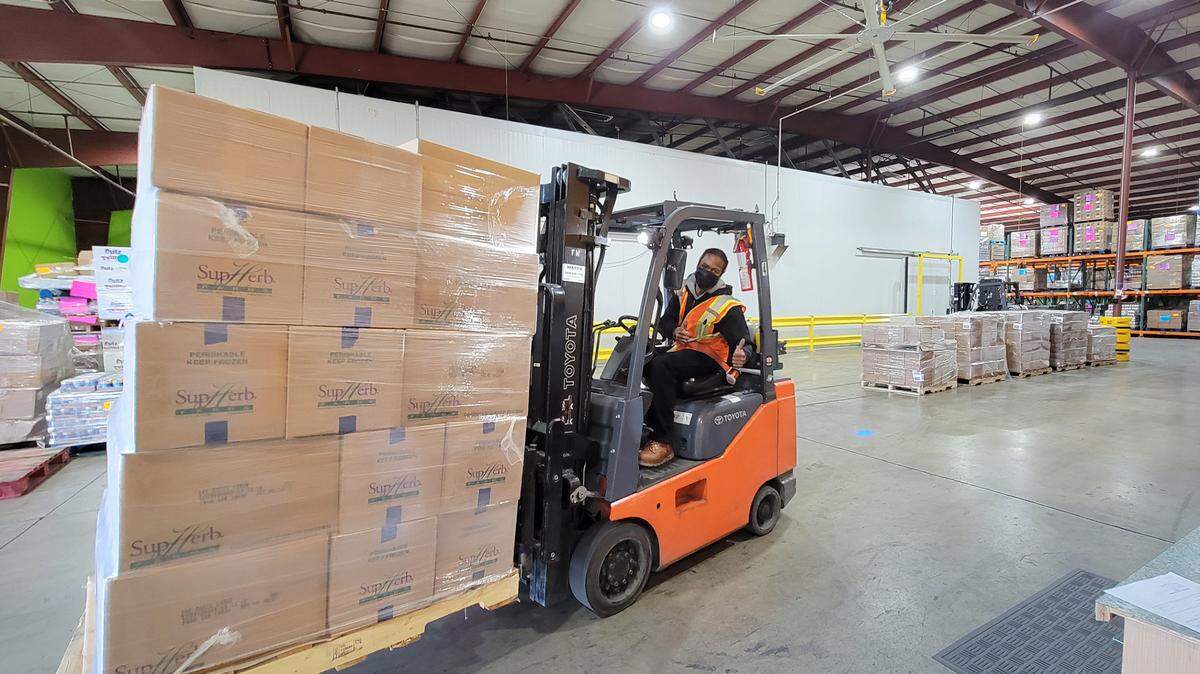 A forklift driver handles some of the food donated by Foster Farms to Second Harvest of the Greater Valley in Manteca, Calif., on Feb. 7, 2022.