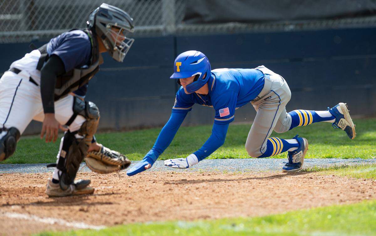 Turlock’s Carter Crivelli beats the throw to Downey catcher Andre Mendoza during the Central California Athletic league game at Downey High School in Modesto, Calif., Thursday, March 23, 2023. Turlock won the game 5-2.