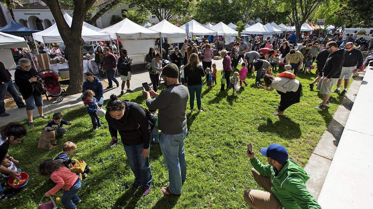 Small children gather up egg treats during the 2017 Easter egg hunt at the Modesto Farmers Market.