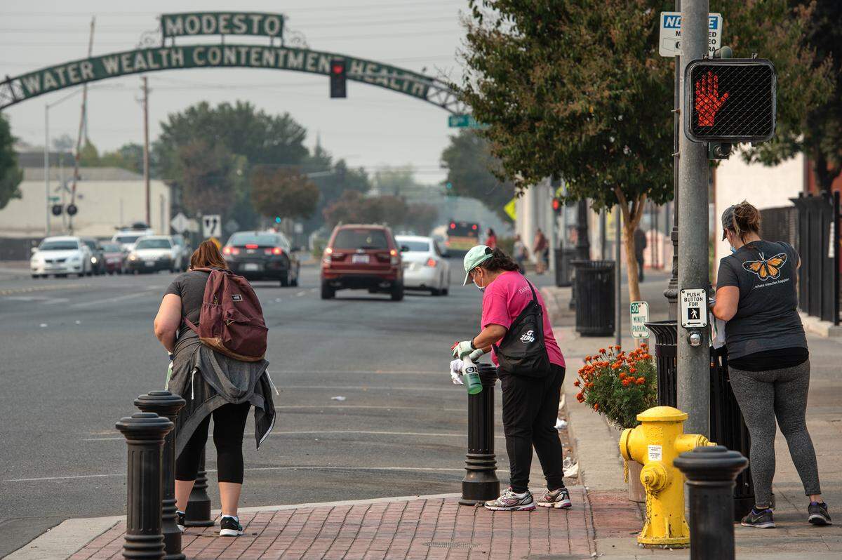 Volunteers Jennifer Tuggle, left, Teressa Cox, middle, and Misty Jones, right, sanitize surfaces on I Street during Love Modesto in Modesto, Calif., on Saturday, Oct. 3 2020.