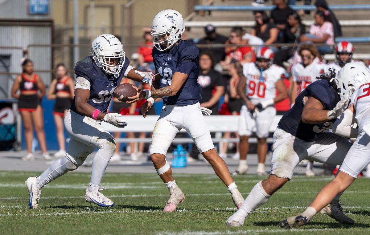 Modesto JC quarterback DayDay Tafoya hands the ball to running back Aiden Muhammad during a Valley Conference game against Fresno City College at Modesto Junior College on Saturday, Oct. 11, 2025.