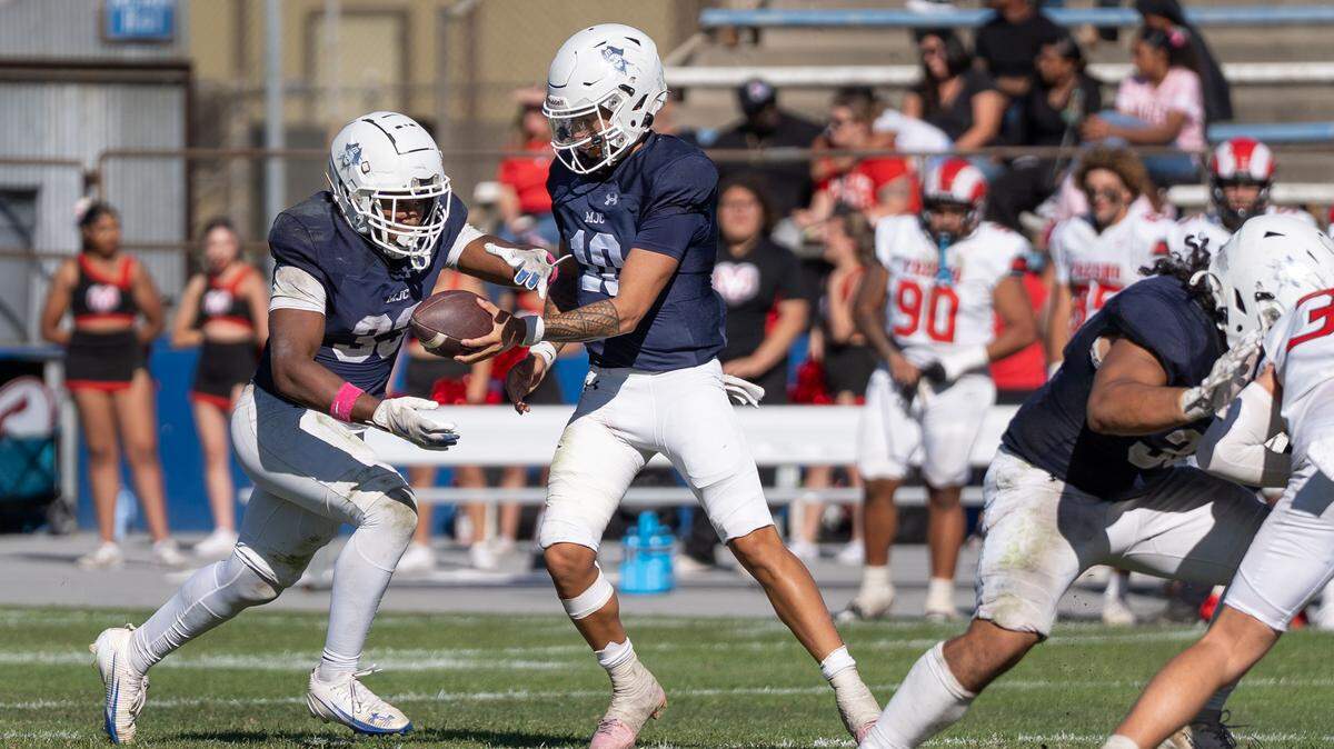 Modesto JC quarterback DayDay Tafoya hands the ball to running back Aiden Muhammad during a Valley Conference game against Fresno City College at Modesto Junior College on Saturday, Oct. 11, 2025.