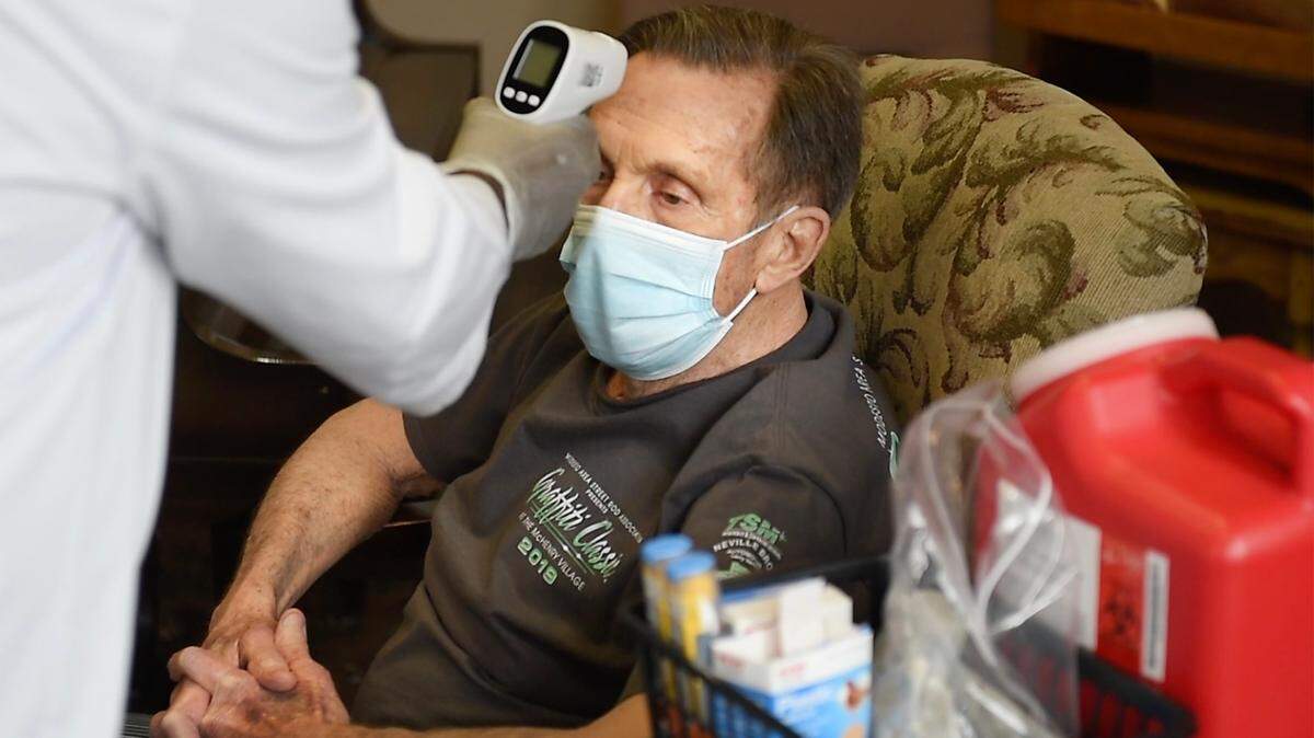 Daryl Dinelli, 78, has his temperature checked before he received the COVID-19 vaccine at Casa de Modesto Retirement Center in Modesto, Calif., on Thursday, Jan. 7, 2021. The injection was administered by a CVS employee who did not want to be pictured. CVS did not allow photographs of their staff or or the preparation of the vials of the Pfizer vaccine.